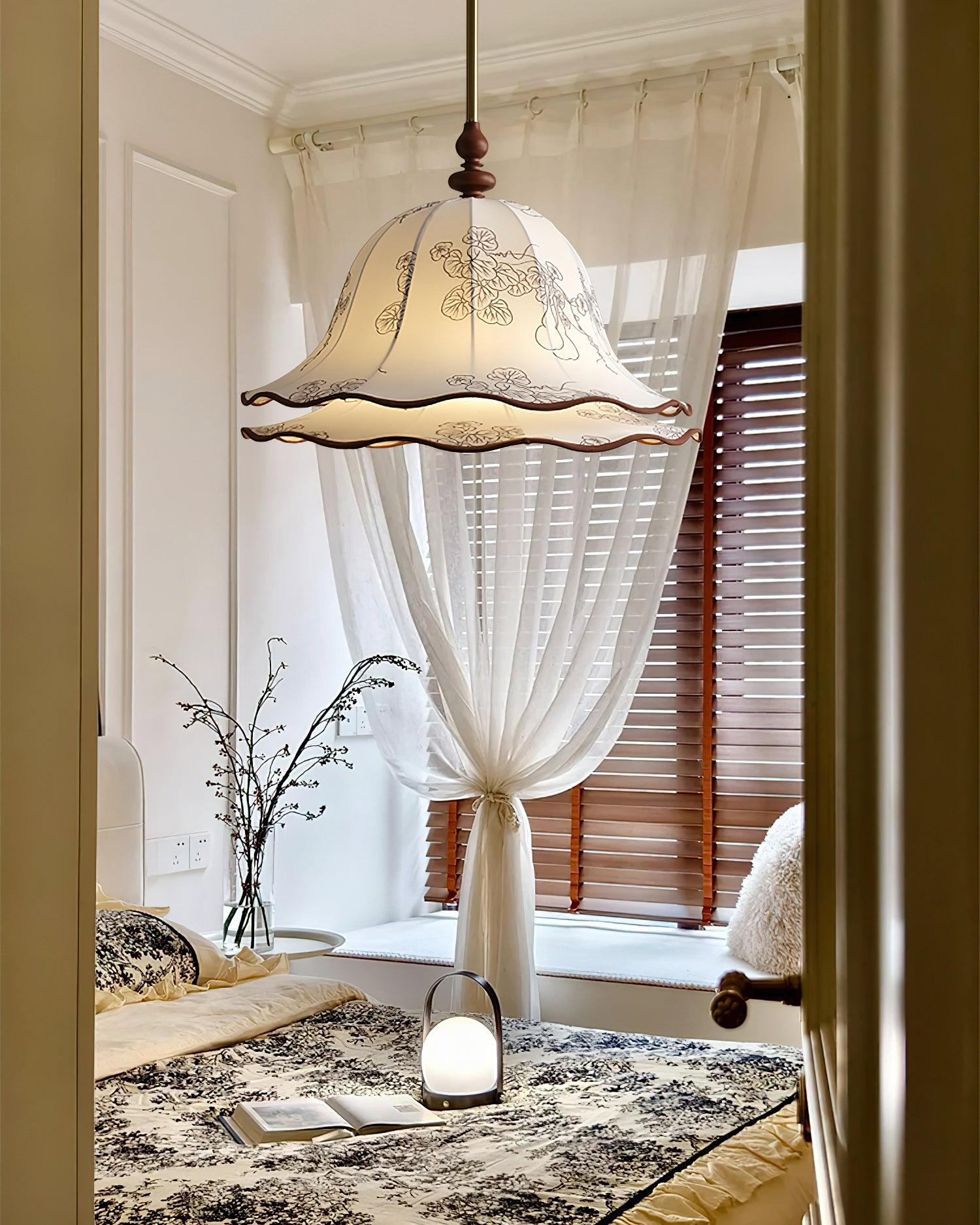 Decorative pendant light hanging above a table with a vase and candle in a room with white curtains.