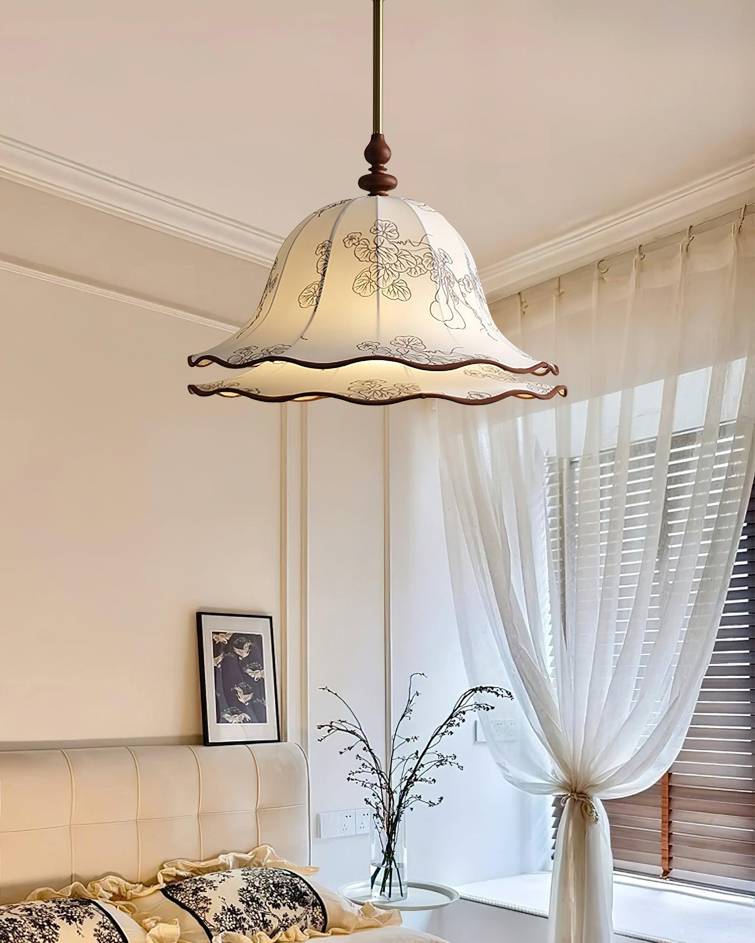 Decorative pendant light hanging above a bed in a bedroom with white curtains and a framed picture on the wall.