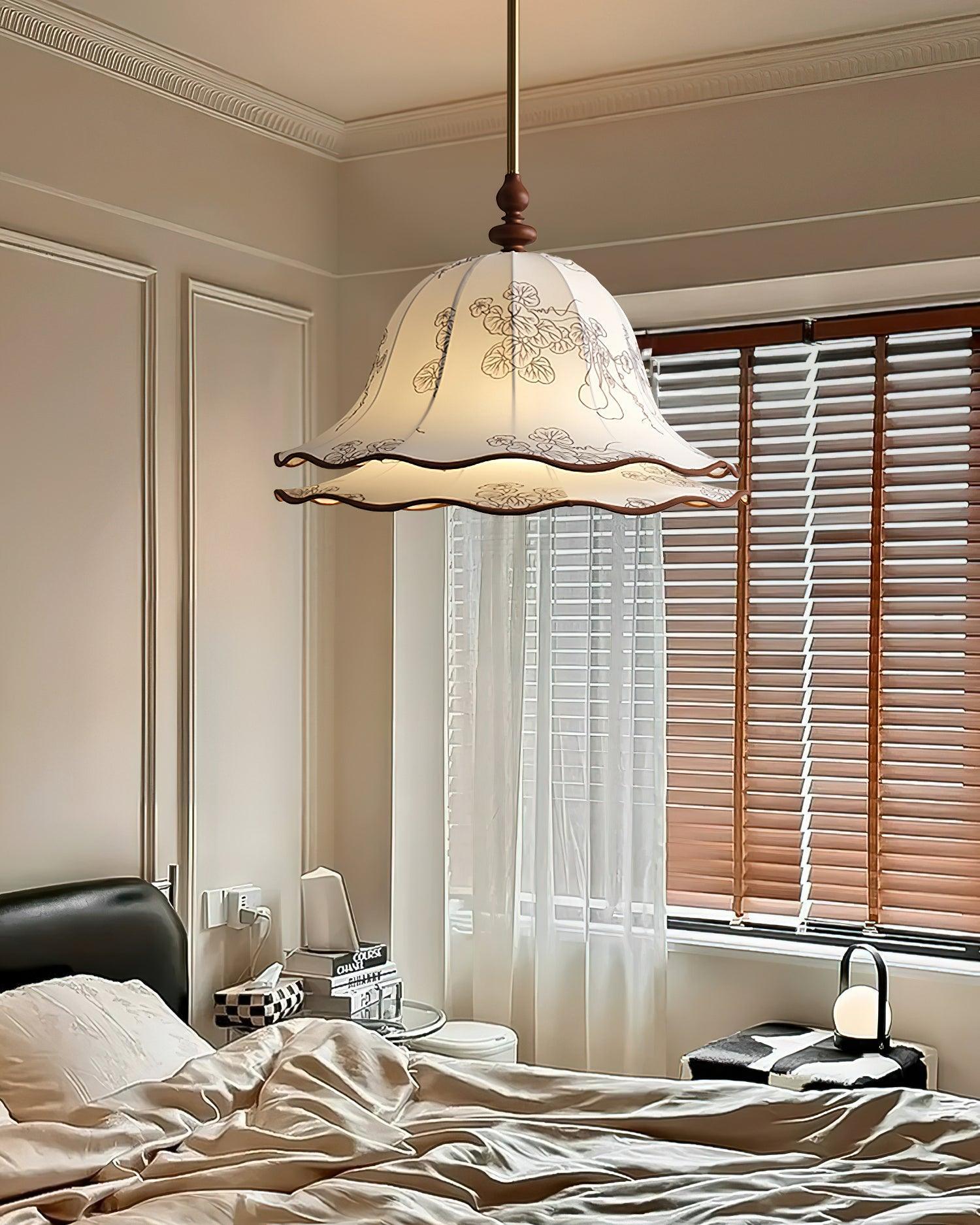 Decorative pendant light hanging above a bed in a bedroom with curtains and a window.