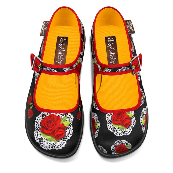 Chocolaticas® Andalucia Women's Mary Jane Flat - Pair of black shoes with red roses and yellow insoles on a white background