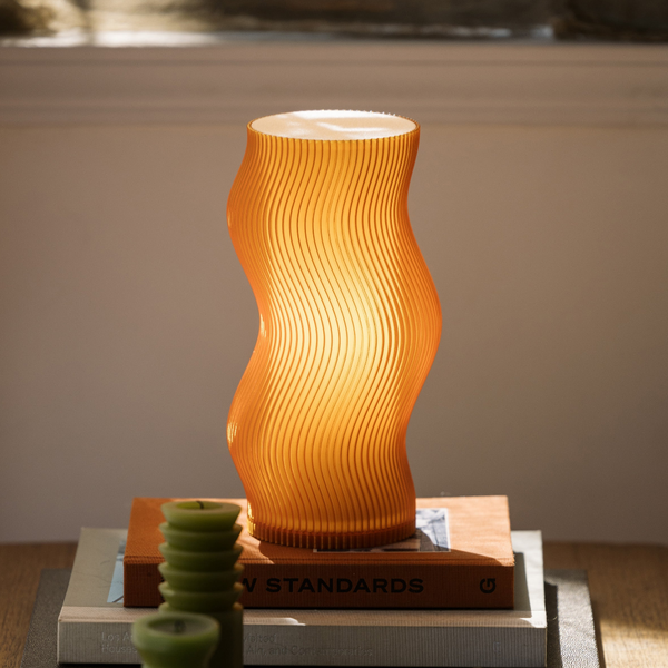 Wavy-patterned orange lamp on a surface with a blurred background