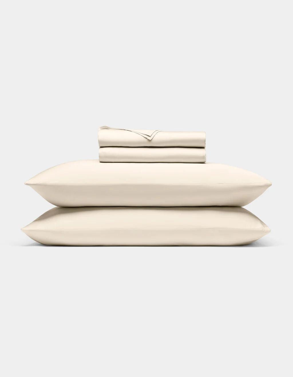 Creme pillows and a folded sheet on a light gray background