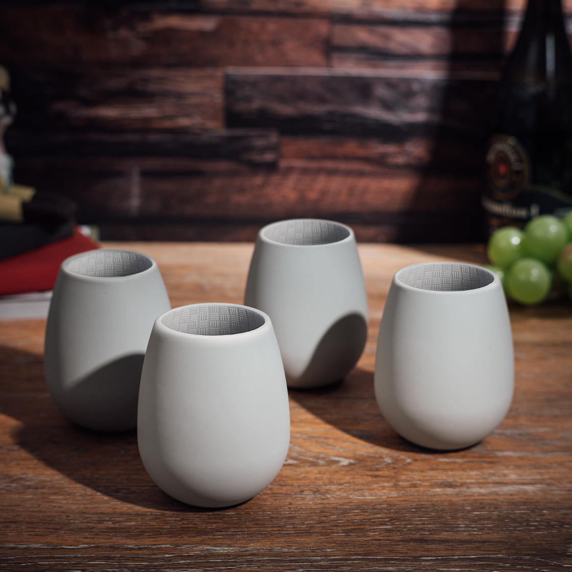 Four gray ceramic cups on a wooden surface with a blurred background
