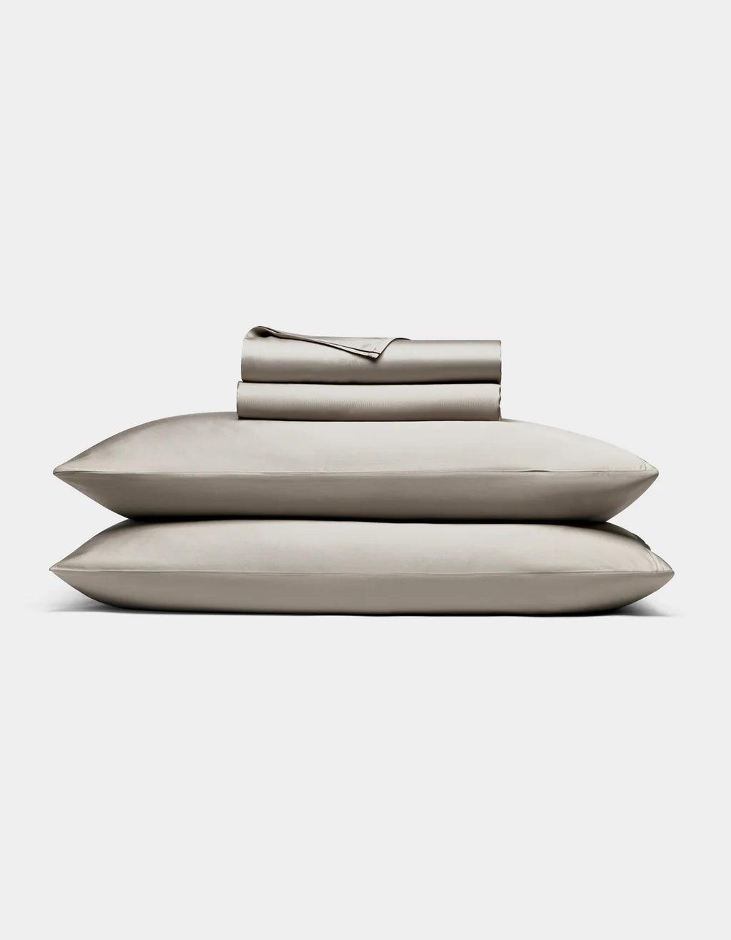 Dove Grey - bedding set with pillows and a folded sheet on a light gray background
