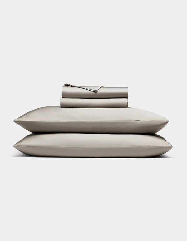 Dove Grey - bedding set with pillows and a folded sheet on a light gray background
