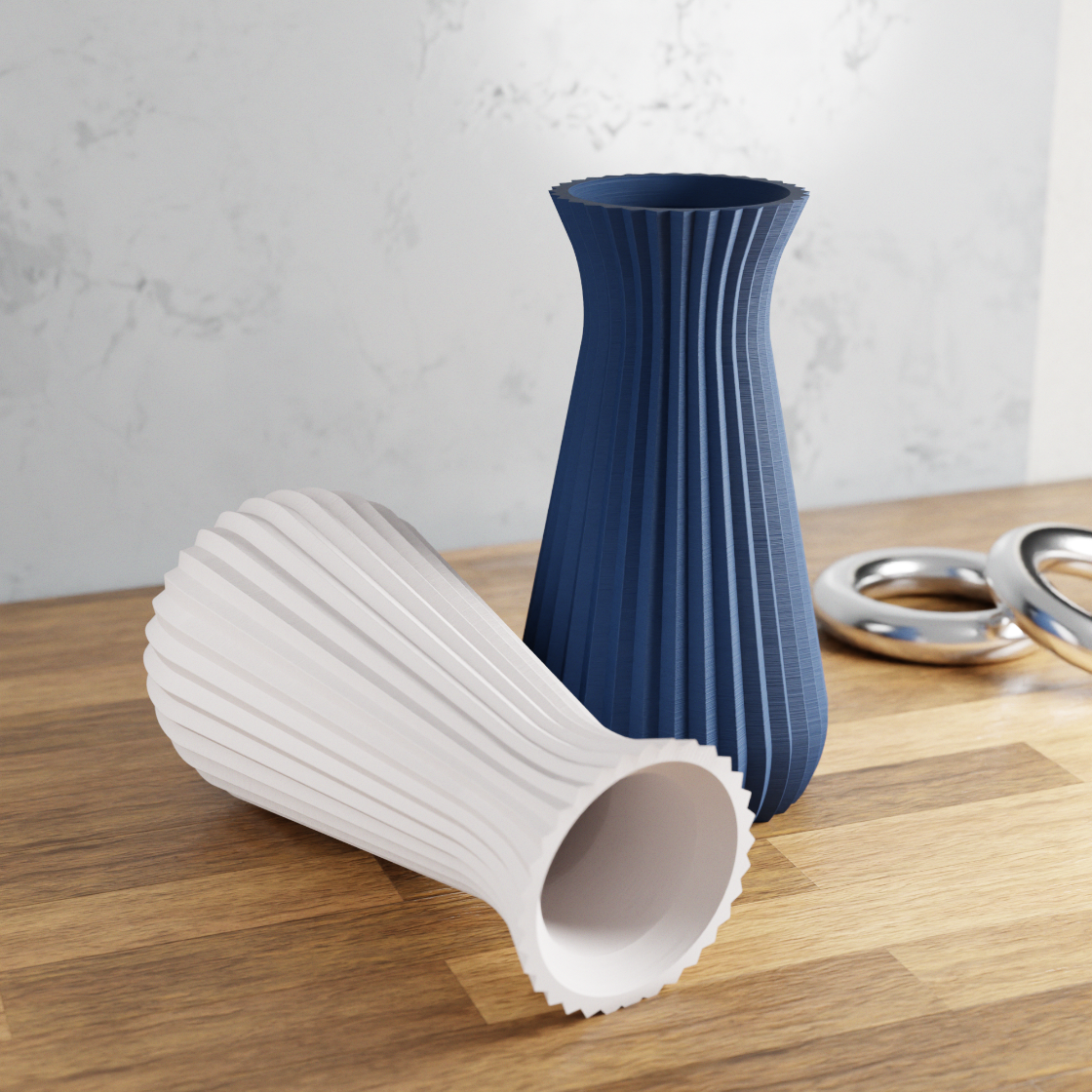 Two textured vases, one white and one blue, on a wooden surface with a light gray background.