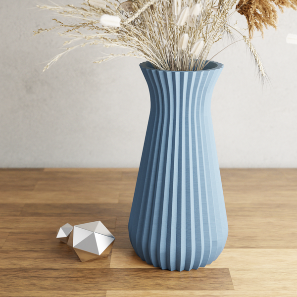 Blue ribbed vase with dried plants on a wooden surface