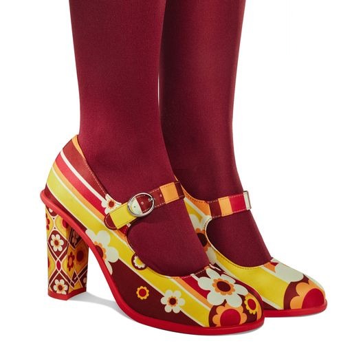Colorful high-heeled shoes with floral patterns worn on red tights against a white background