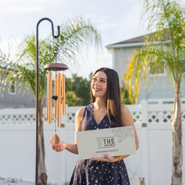Woman holding a wind chime and its packaging outdoors