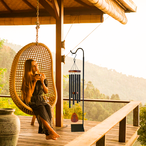 Person sitting in a wicker chair on a wooden deck with a scenic view of mountains.