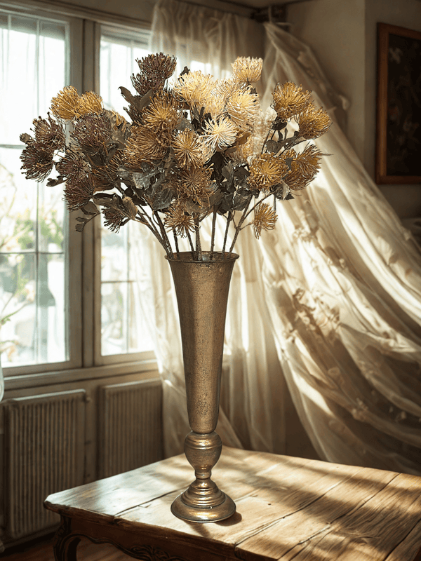 Decorative vase with flowers on a wooden table in a room with curtains and a radiator.