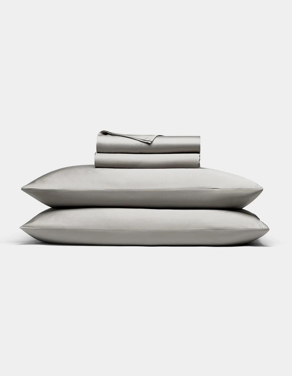 Light Grey bedding including a duvet, two pillows, and a folded blanket on a white background.