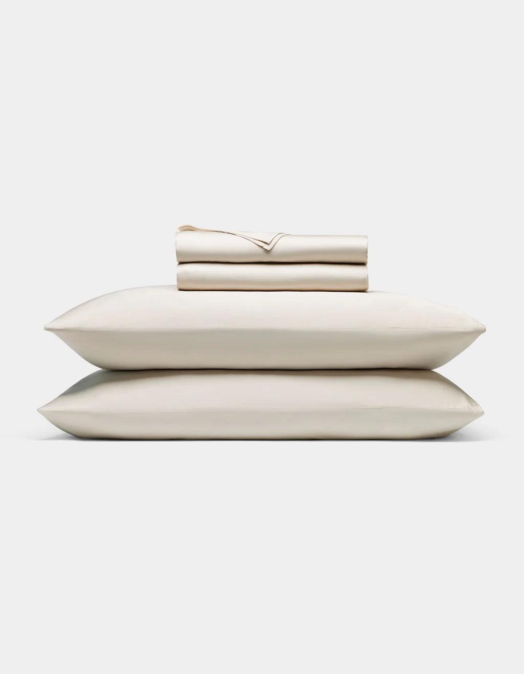 Oat - Set of beige pillows and a folded blanket on a white background