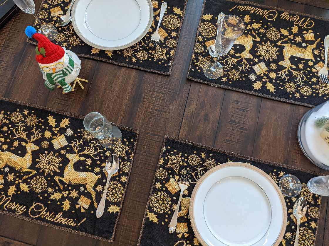 Christmas-themed placemats with gold reindeer and snowflakes on a wooden table.