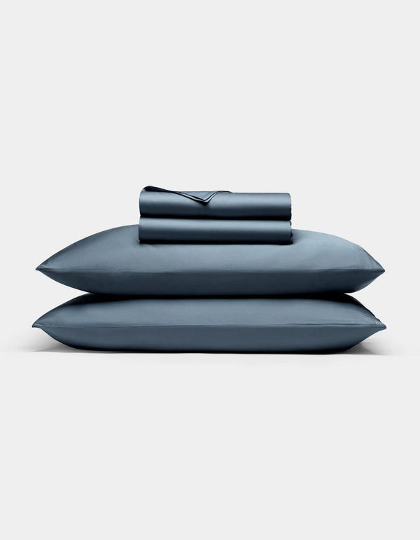 Pacific Blue - Set of blue bedding including a pillow and two folded sheets on a light gray background