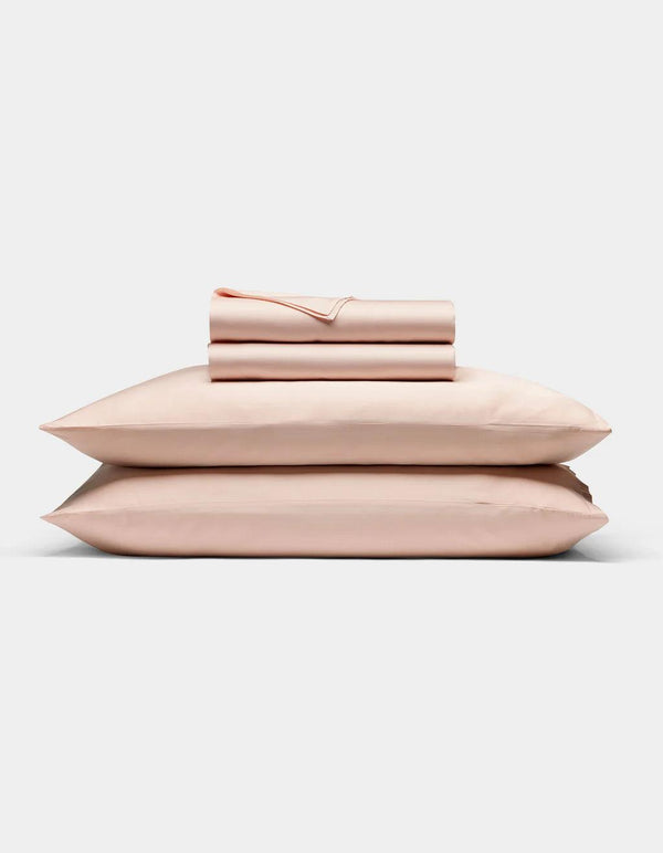 Peony - Set of pink bedding including a duvet, two pillows, and a folded blanket on a light gray background.