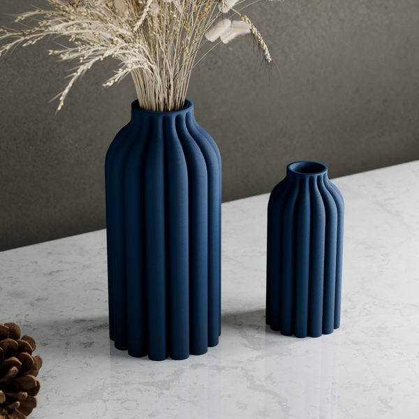 Two blue textured vases on a marble surface with a gray background