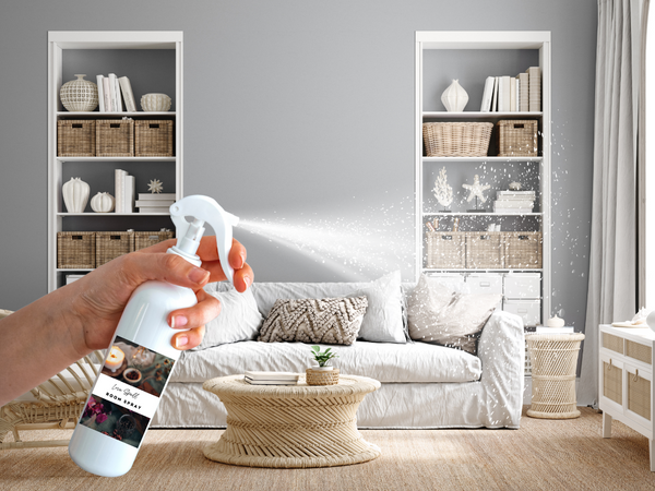 Person using a spray bottle in a living room with a gray wall and white bookshelves.