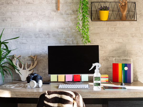 Home office desk with computer monitor, keyboard, and decor items against a brick wall.