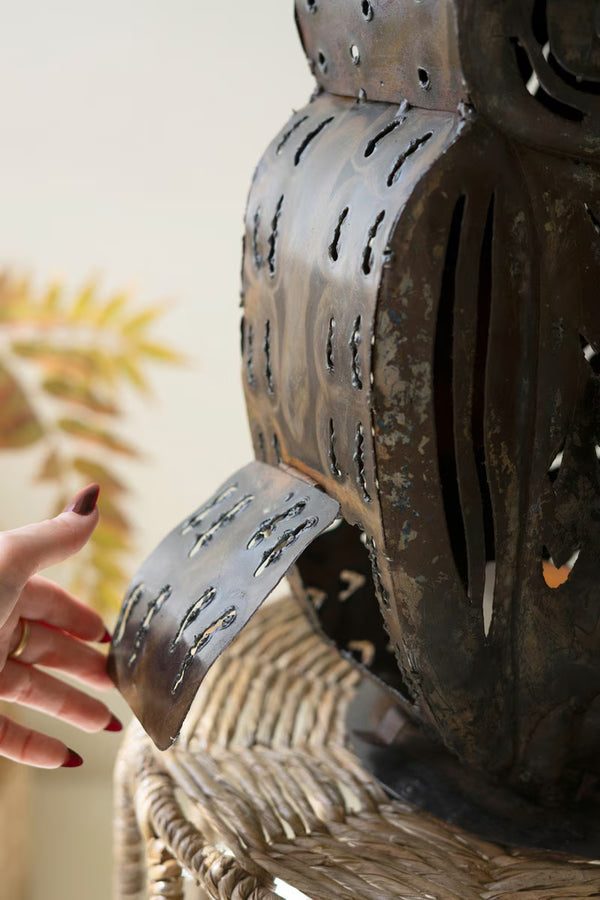 Metallic owl-shaped object with a hand interacting with it, blurred background