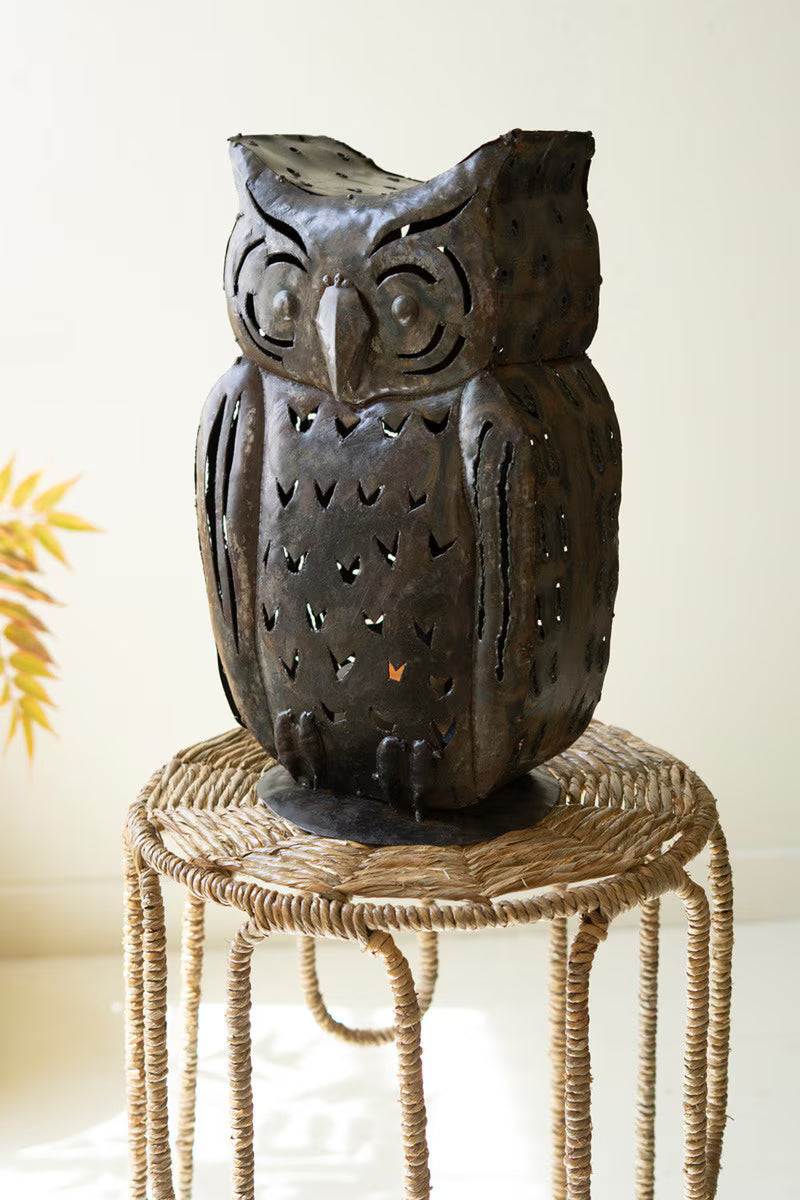 Decorative owl-shaped lantern on a woven stool with a blurred background