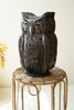 Decorative owl-shaped lantern on a woven stool with a blurred background