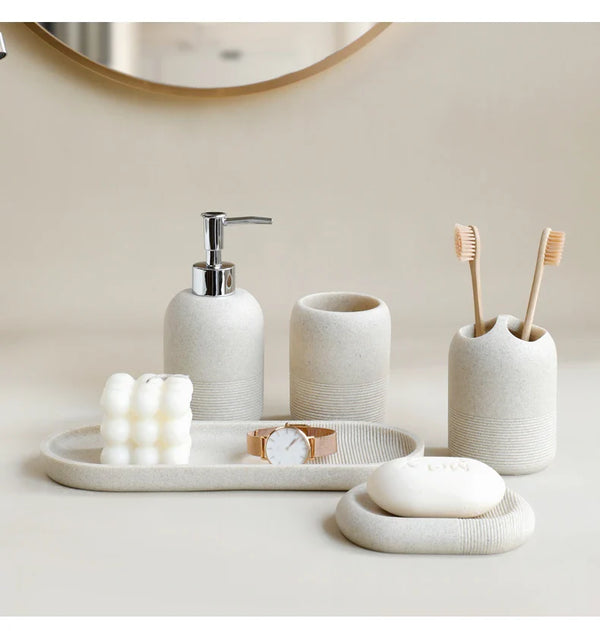 Beige 5Pcs Bathroom Accessories set by Buddify with soap dispenser, tumbler, and tray styled with candle and watch for decor inspiration.