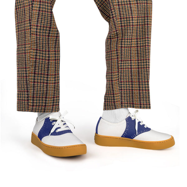 White sneakers with blue accents and brown soles worn with plaid pants on a white background