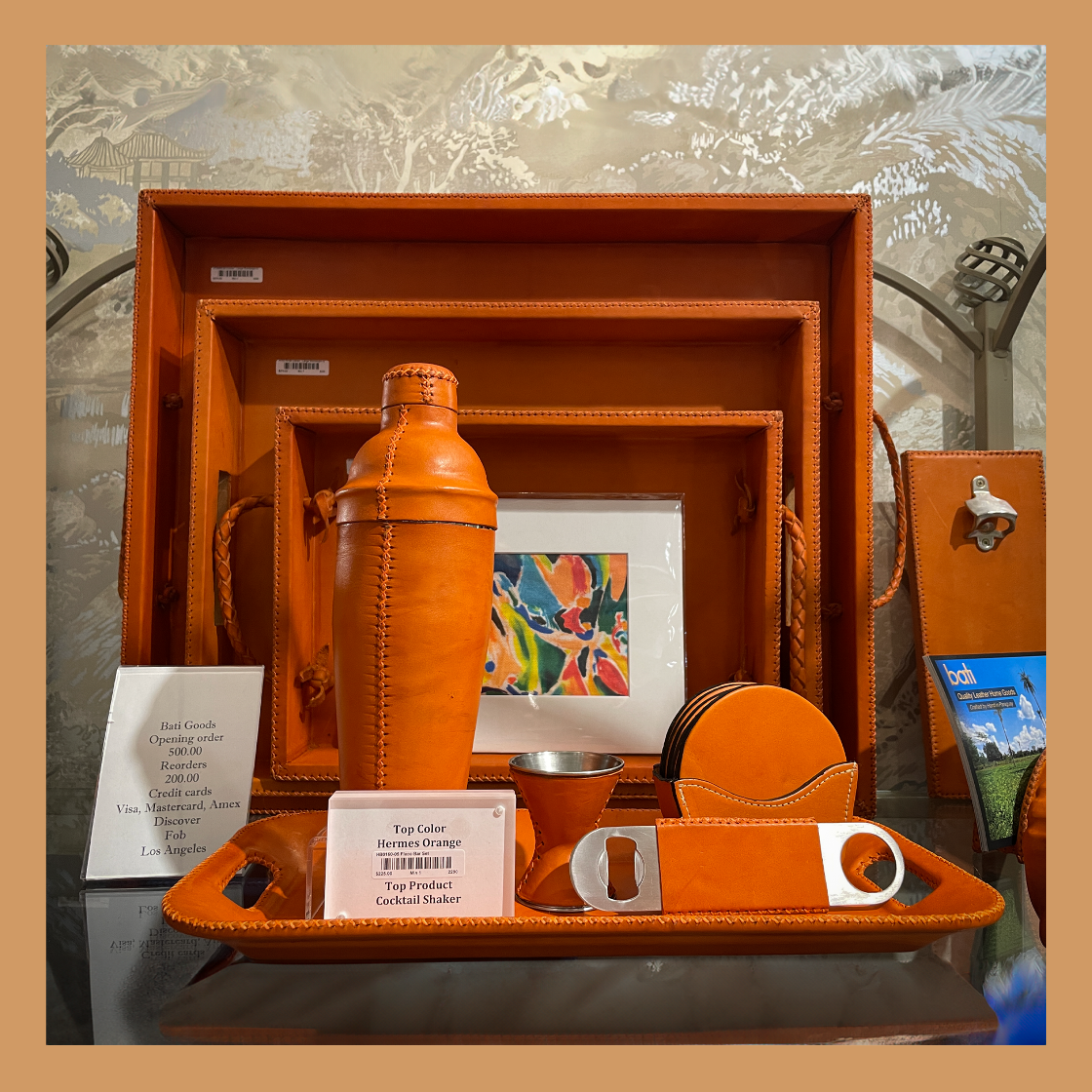 Orange leather bar set with shaker, tray, and other accessories on a decorative surface.