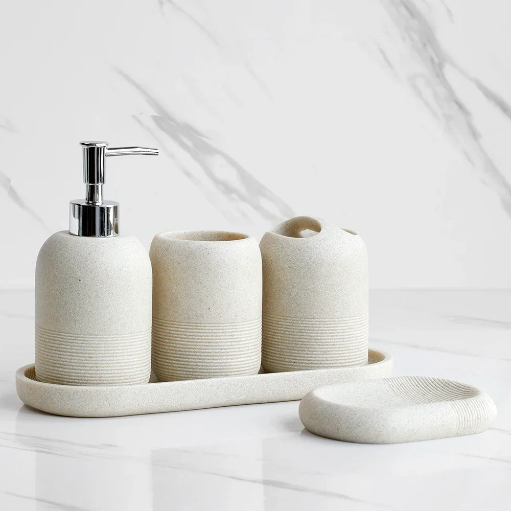 Beige 5Pcs Bathroom Accessories set by Buddify with soap dispenser, tumbler, toothbrush holder, and soap dish on tray in marble bathroom.