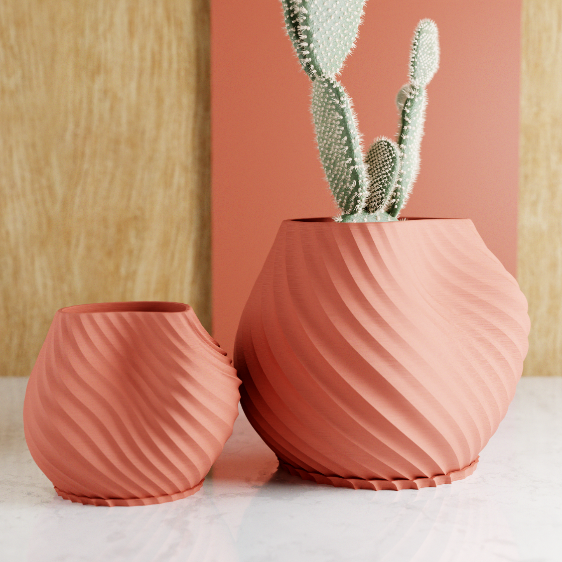 Two pink textured vases with a cactus on a light wooden surface.