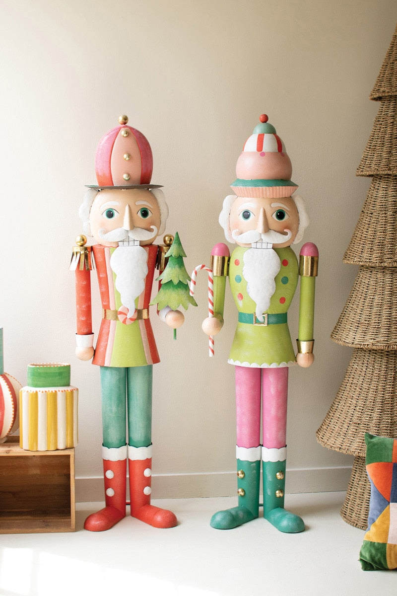 Colorful nutcrackers standing next to a Christmas tree and presents on a white floor.