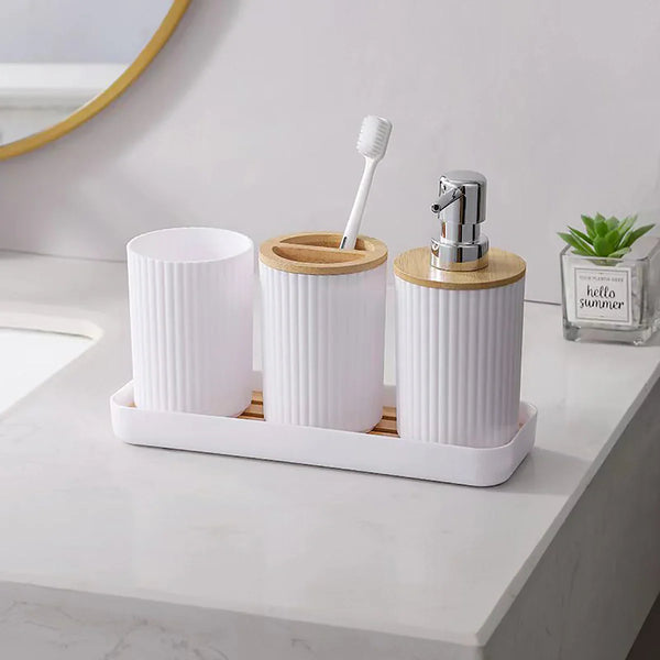 White Buddify bathroom accessories set with bamboo lids on vanity, includes soap dispenser, toothbrush holder, and cotton jar on matching tray.