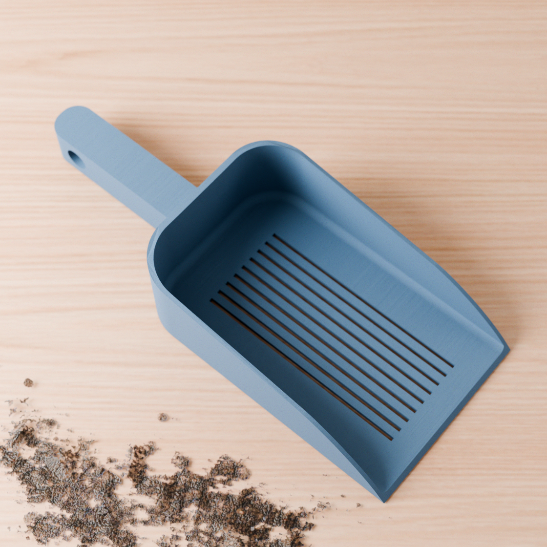 Blue scoop for cat litter on a wooden surface with scattered litter.