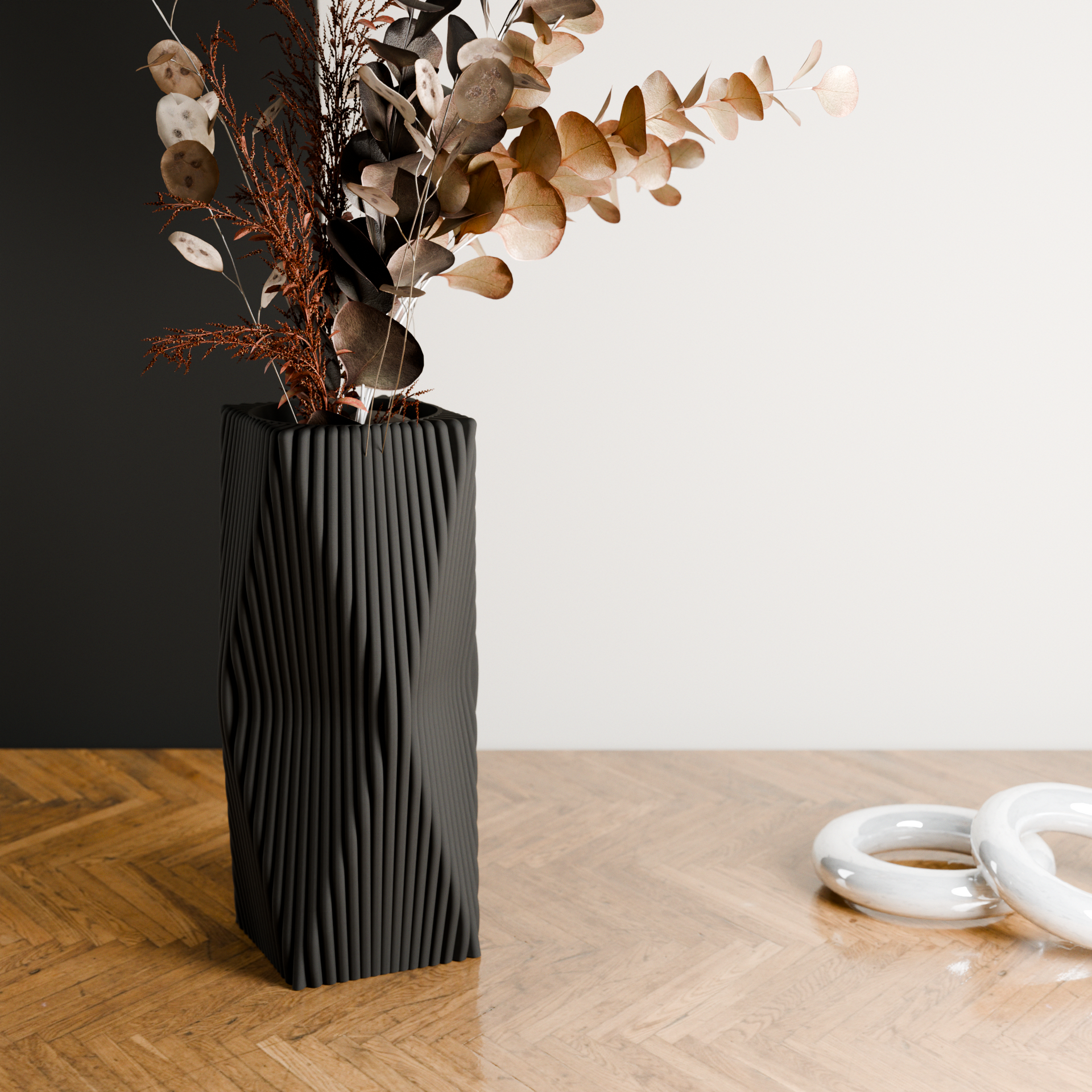 Black textured vase with dried flowers on a wooden floor