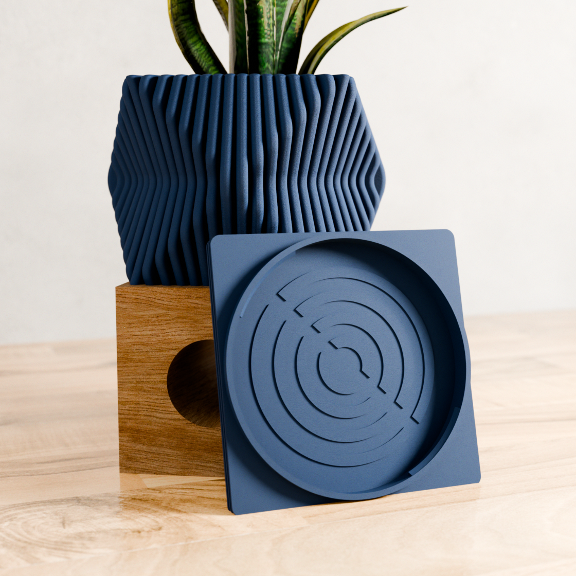 Blue geometric planter and matching tray on a wooden surface with a light background