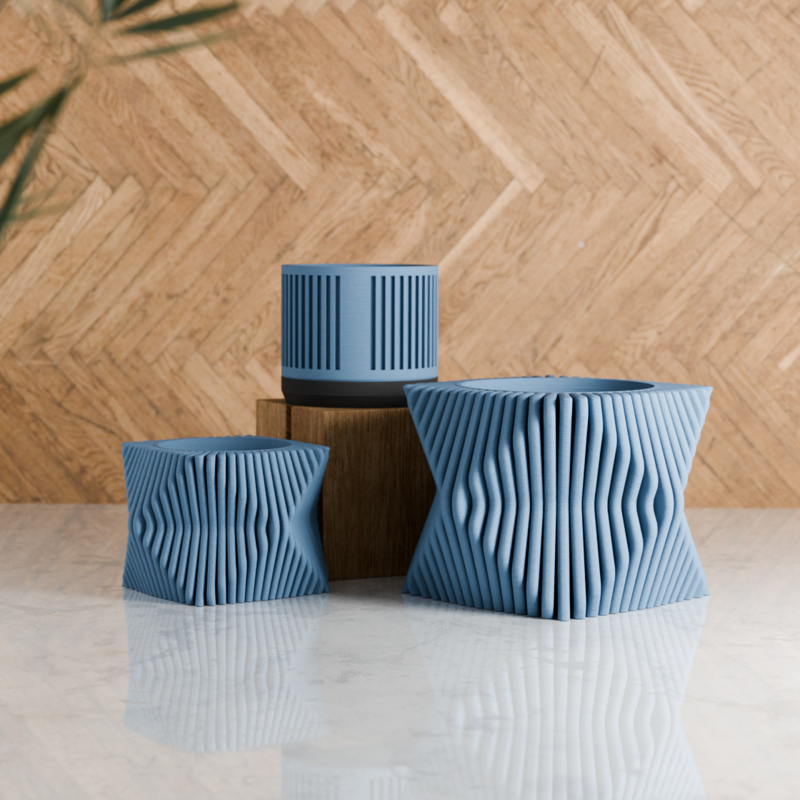 Three blue textured planters on a reflective surface with a wooden wall background