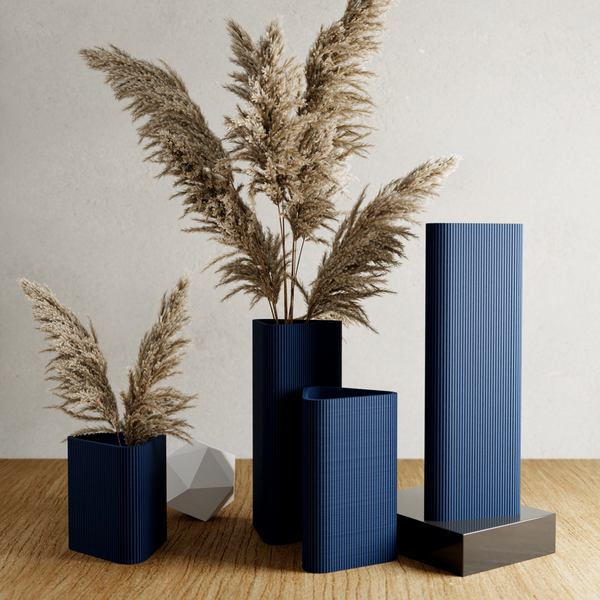Set of blue vases with dried plants on a wooden surface