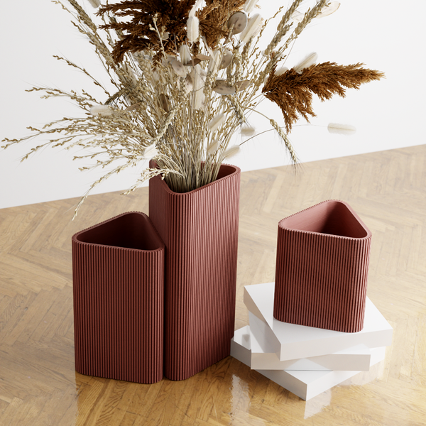 Three ribbed vases on a wooden surface with dried plants.