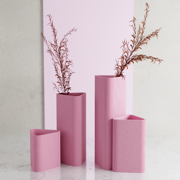 Set of four pink ribbed vases with dried plants on a light background