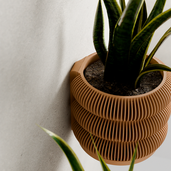 Brown ribbed wall planter with a plant against a light gray wall