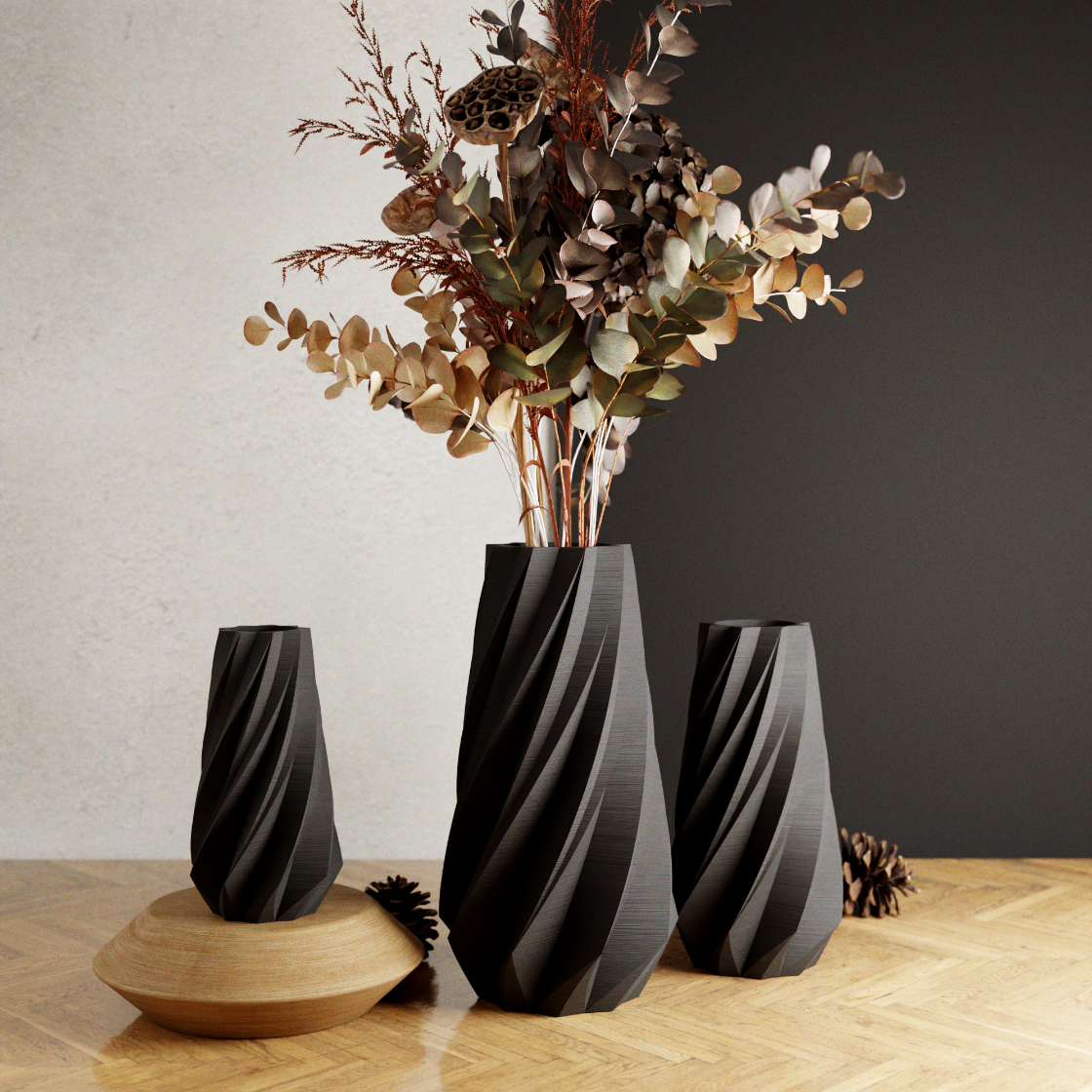 Three black textured vases on a wooden surface with a vase containing dried flowers.