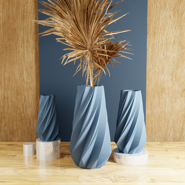Three blue textured vases with dried plants on a wooden floor against a dark blue wall.