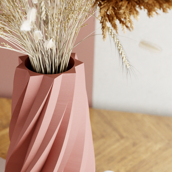 Pink vase with dried plants on a wooden surface