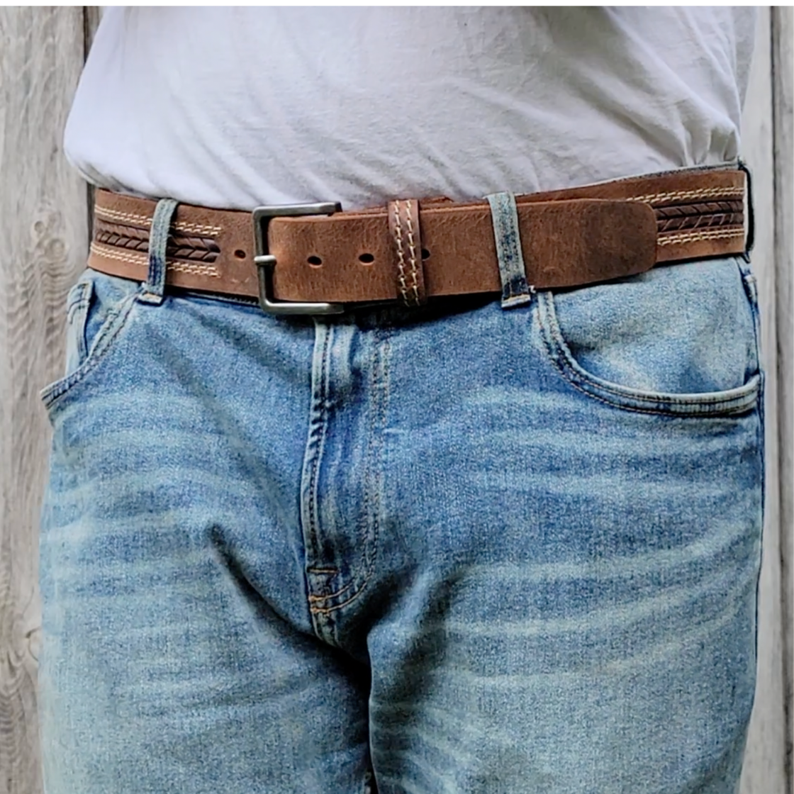Person wearing blue jeans and a brown belt with a visible buckle.