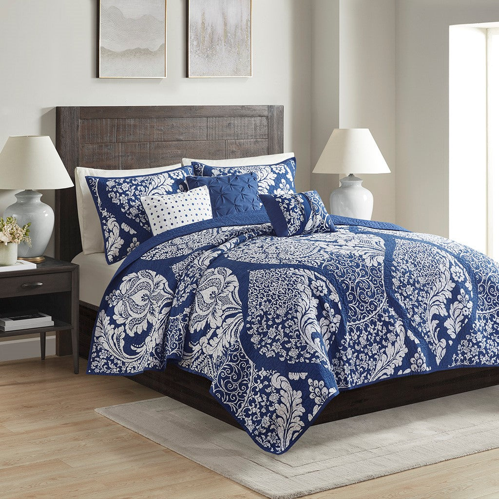 Vienna 6 Piece Printed Cotton Quilt Set with Throw Pillows by Madison Park. Indigo and white patterned bedding set on a bed in a bedroom with lamps and decor.