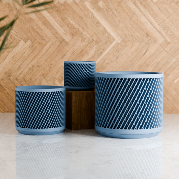 Three blue textured planters of different sizes on a light surface with a wooden background