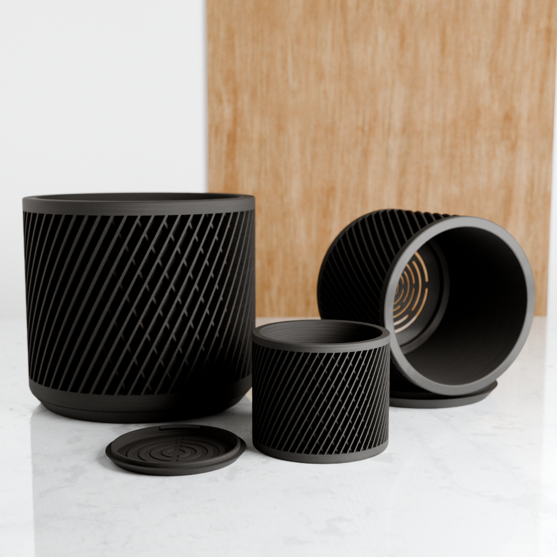 Set of black textured planters on a white surface with a wooden board in the background