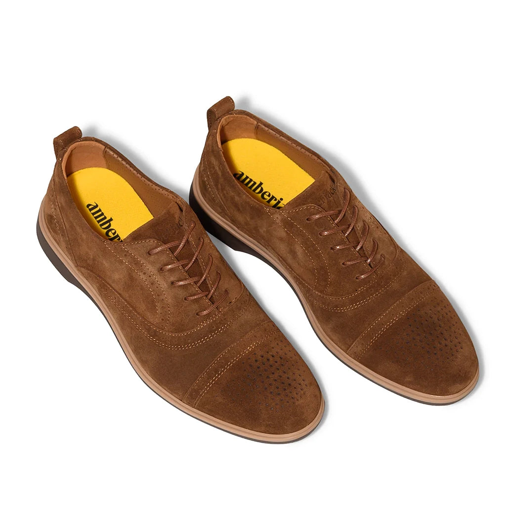 Brown suede shoes with yellow lining on a white background