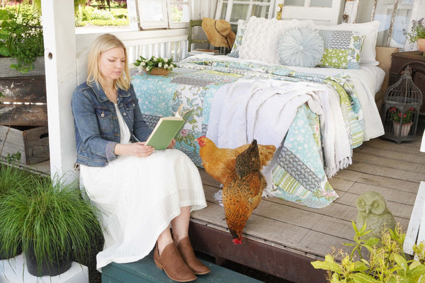 Woman reading a book on a porch with a chicken nearby